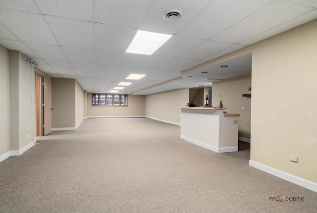 basement with a paneled ceiling and carpet flooring