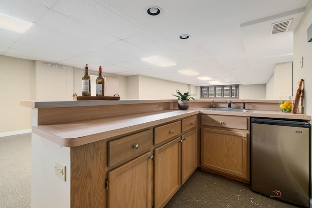 kitchen with a paneled ceiling, dishwasher, sink, kitchen peninsula, and stainless steel refrigerator