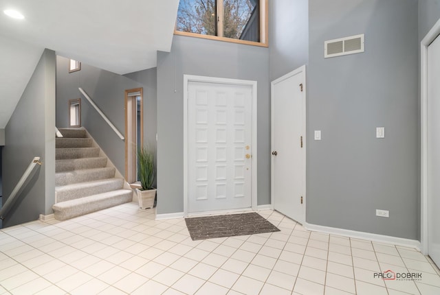 foyer featuring light tile patterned flooring and a high ceiling