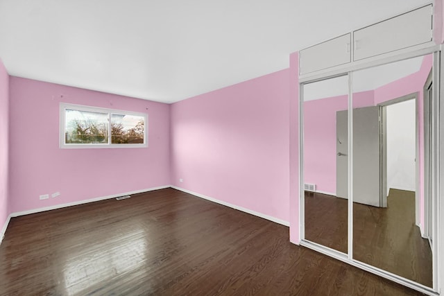 unfurnished bedroom featuring dark wood-type flooring and a closet