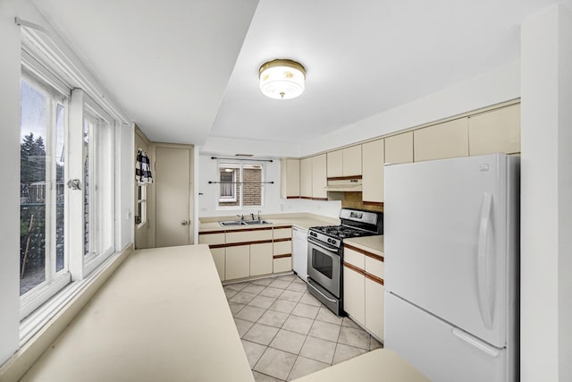 kitchen featuring sink, cream cabinets, white refrigerator, and stainless steel gas range