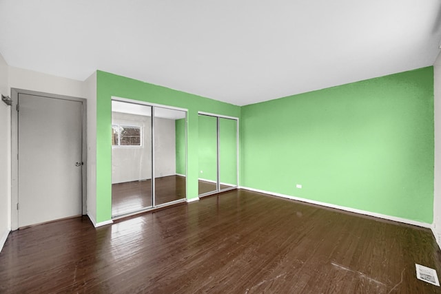 unfurnished bedroom with two closets and dark wood-type flooring