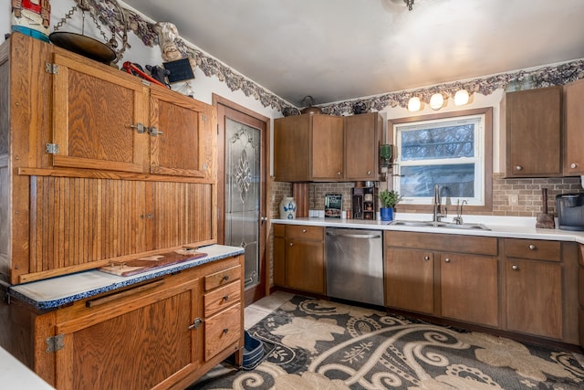 kitchen featuring a sink, backsplash, dishwasher, and brown cabinetry