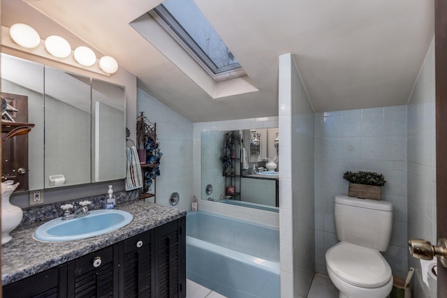 full bath with tile walls, lofted ceiling with skylight, toilet, a tub to relax in, and vanity