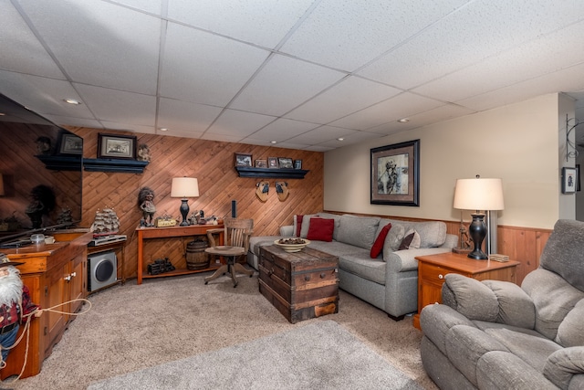 living area featuring carpet flooring, a paneled ceiling, recessed lighting, and wood walls