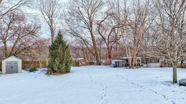 snowy yard with a storage unit, an outdoor structure, and fence