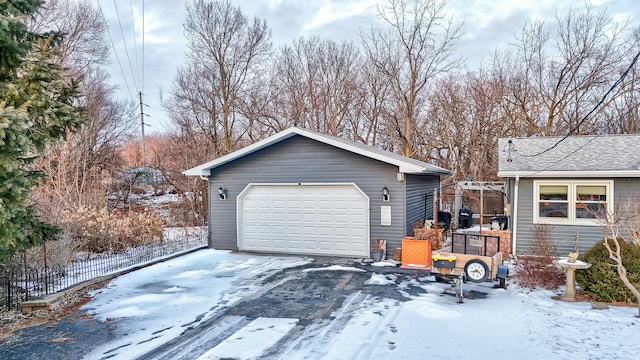 snow covered garage with a garage and fence