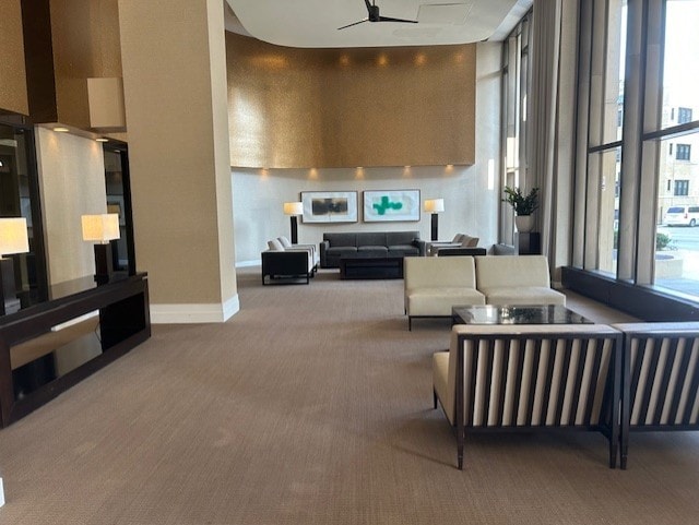 living room featuring a healthy amount of sunlight, ceiling fan, expansive windows, and carpet flooring