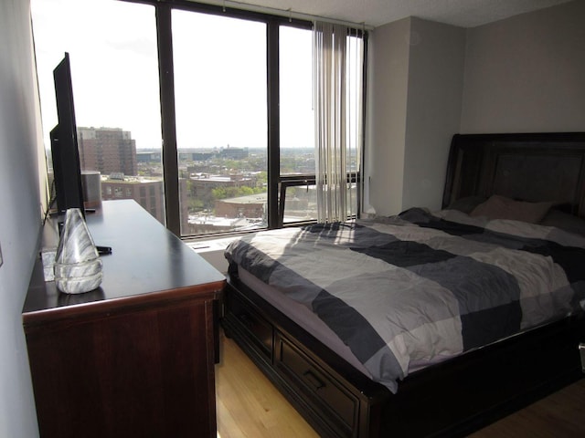 bedroom with a wall of windows and light hardwood / wood-style flooring