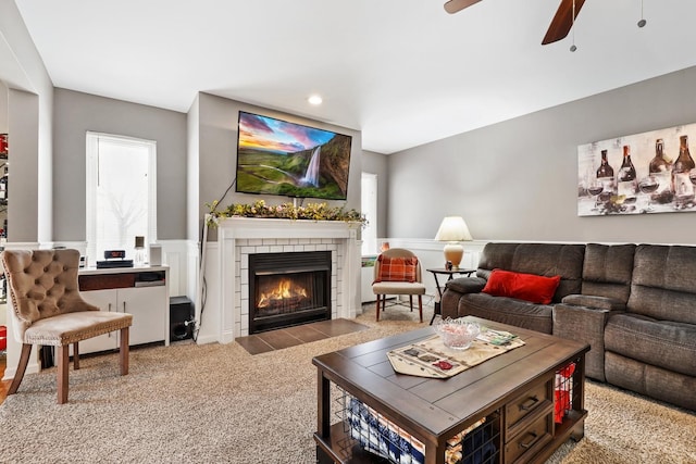 living room featuring ceiling fan, light carpet, and a fireplace