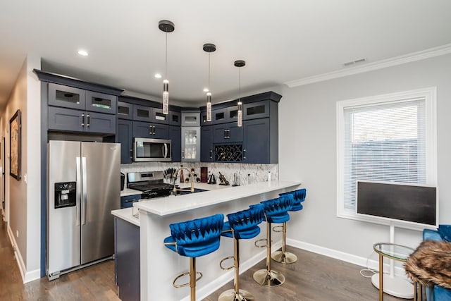 kitchen featuring decorative backsplash, kitchen peninsula, a breakfast bar, stainless steel appliances, and hanging light fixtures