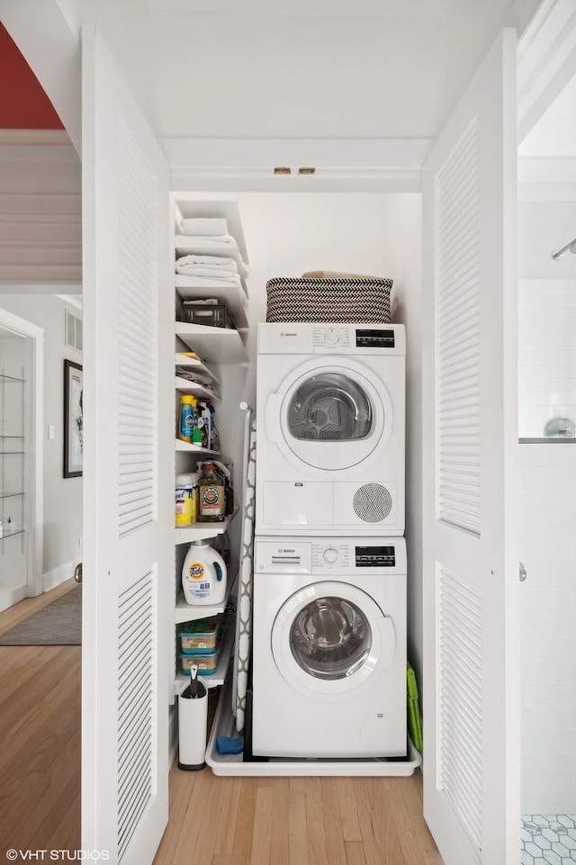 washroom with wood-type flooring and stacked washer / drying machine