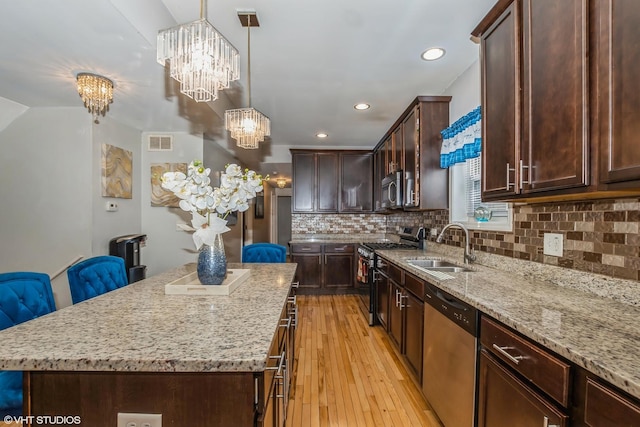 kitchen featuring a center island, sink, decorative light fixtures, appliances with stainless steel finishes, and a notable chandelier