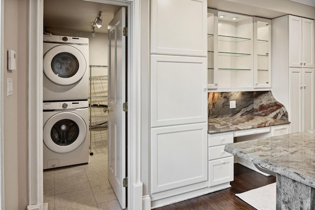 washroom featuring stacked washing maching and dryer and track lighting