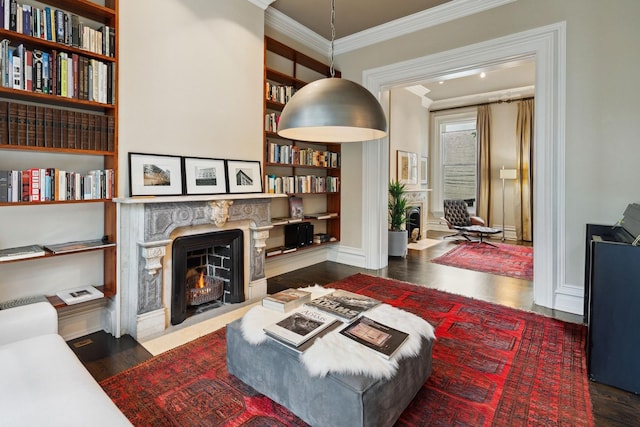 living area with built in shelves, crown molding, and dark wood-type flooring