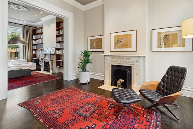 living area with hardwood / wood-style flooring, built in shelves, and ornamental molding