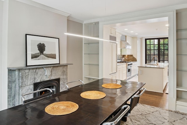 dining room with dark hardwood / wood-style floors, a stone fireplace, crown molding, and sink