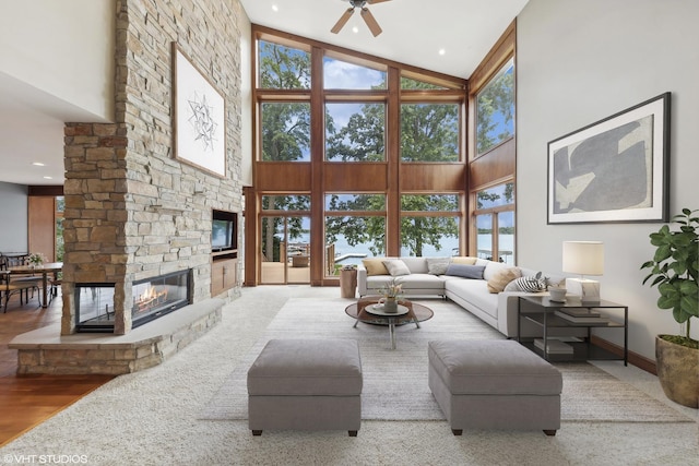 living room with a high ceiling, ceiling fan, a fireplace, and hardwood / wood-style flooring