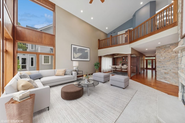 living room with a high ceiling, ceiling fan, and wood-type flooring