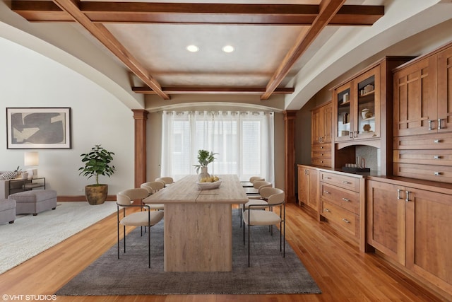 dining space featuring beam ceiling, light hardwood / wood-style floors, and ornate columns