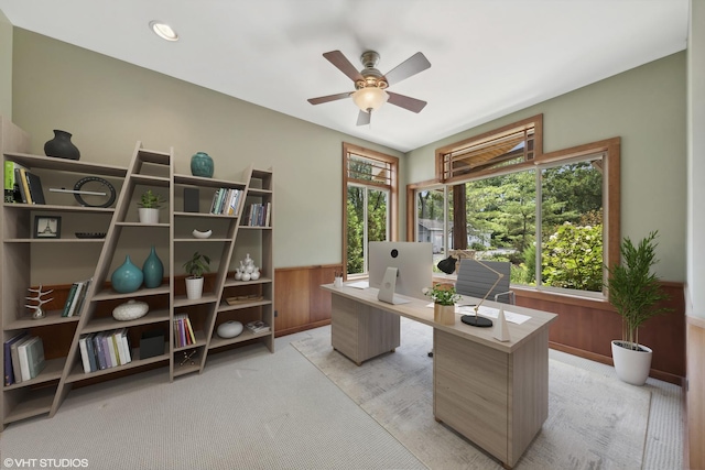 home office featuring ceiling fan, light colored carpet, and wooden walls