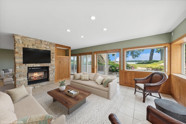 tiled living room featuring wooden walls and a stone fireplace