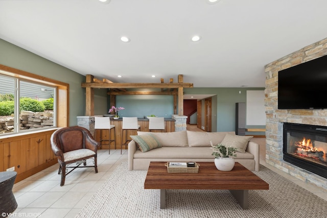 tiled living room featuring a stone fireplace