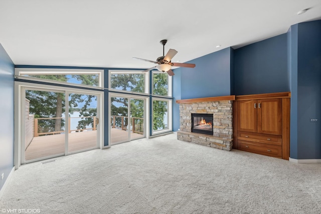 unfurnished living room featuring lofted ceiling, a fireplace, ceiling fan, and light carpet