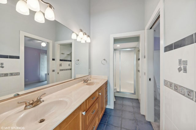 bathroom featuring toilet, tile patterned floors, vanity, tile walls, and a shower with shower door