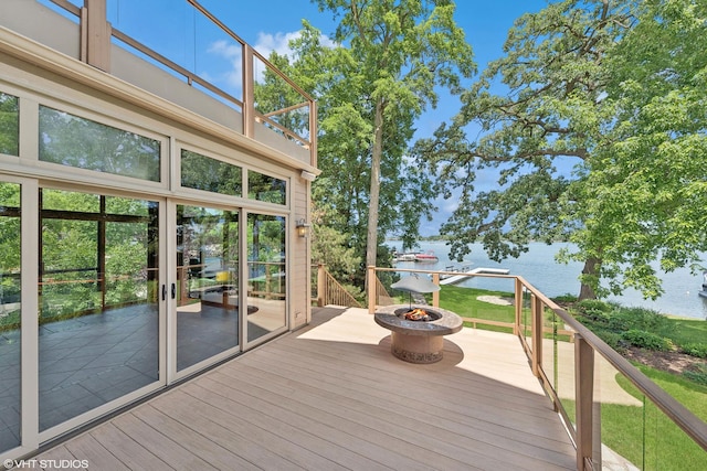 wooden terrace with a fire pit and a water view