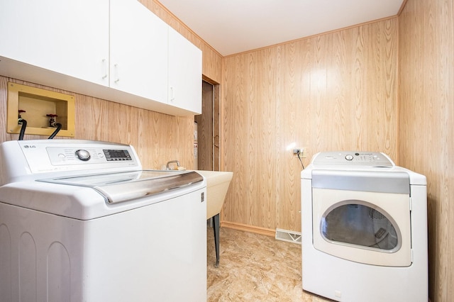 laundry area with washer and clothes dryer, cabinets, and wooden walls