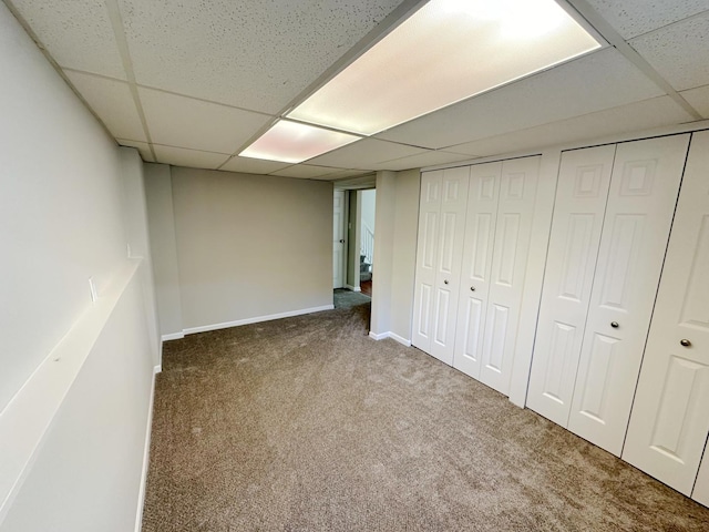 basement featuring a drop ceiling and carpet floors