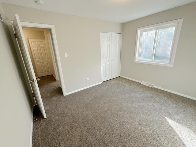 unfurnished bedroom featuring dark carpet and a closet