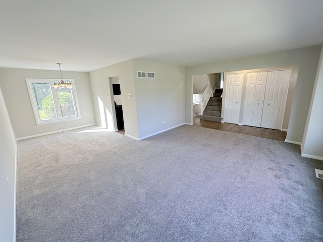 unfurnished living room featuring carpet flooring and an inviting chandelier