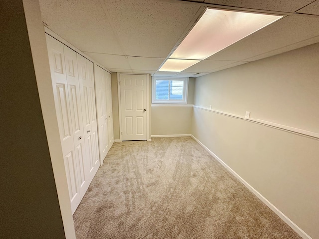 basement with light colored carpet and a drop ceiling