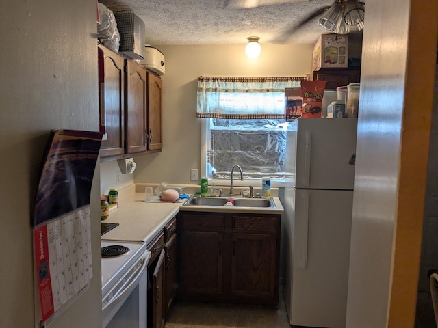 kitchen with tile patterned floors, sink, a textured ceiling, and white appliances