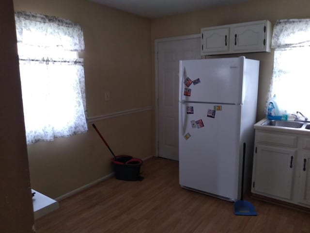 kitchen featuring sink, light hardwood / wood-style floors, white cabinets, and white refrigerator