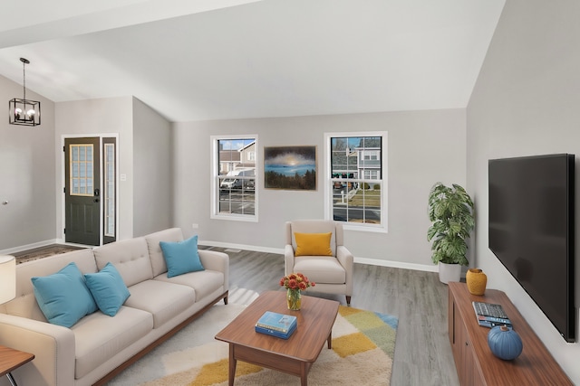 living room with light hardwood / wood-style flooring, lofted ceiling, and a notable chandelier