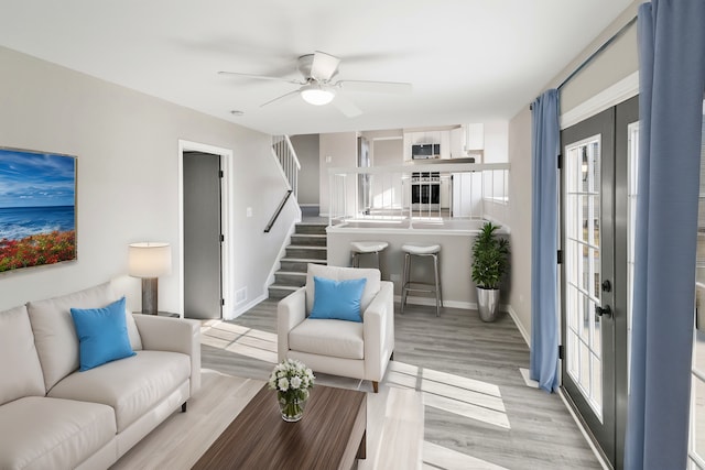 living room with ceiling fan and light hardwood / wood-style flooring