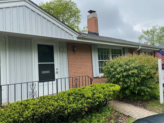 11 Robin Hood Ln, Northfield, IL 60093 - view of exterior entry with a chimney, board and batten siding, and brick siding