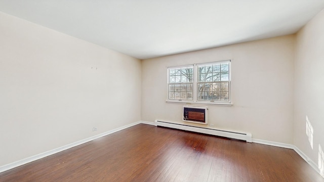 empty room featuring a wall unit AC, a baseboard heating unit, and dark hardwood / wood-style floors