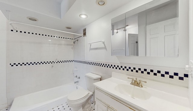 full bathroom with tile walls, tiled shower / bath combo, vanity, and toilet