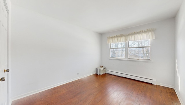 spare room with baseboard heating and dark wood-type flooring