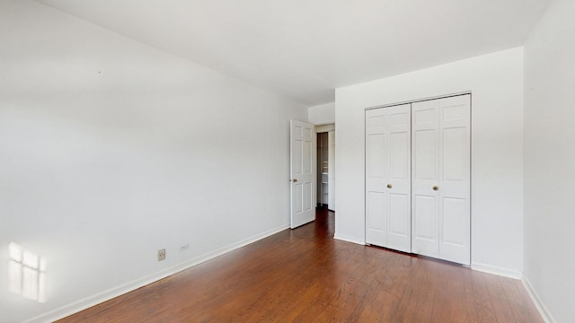 unfurnished bedroom with dark hardwood / wood-style flooring and a closet