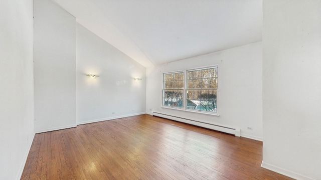 spare room with hardwood / wood-style flooring, baseboard heating, and vaulted ceiling