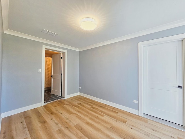 unfurnished bedroom with a closet, crown molding, and light hardwood / wood-style floors