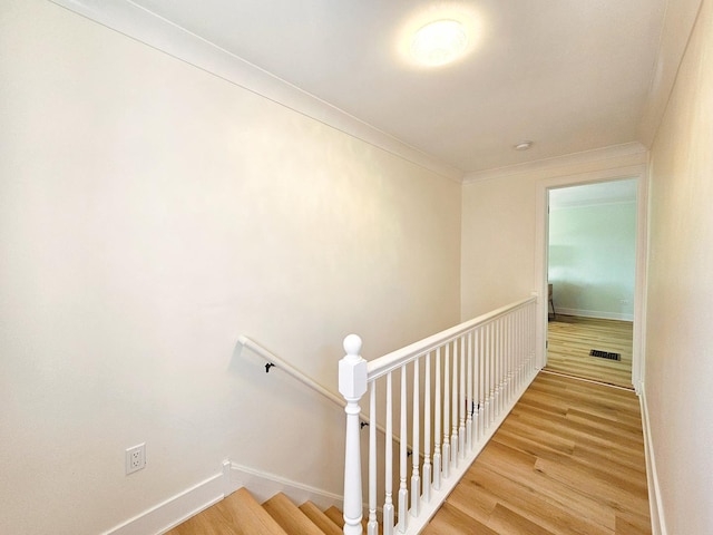 stairway featuring hardwood / wood-style floors and crown molding