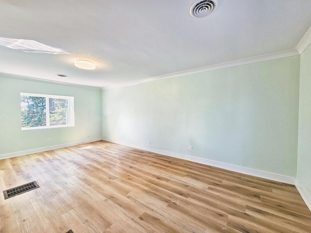 empty room featuring light wood-type flooring and crown molding