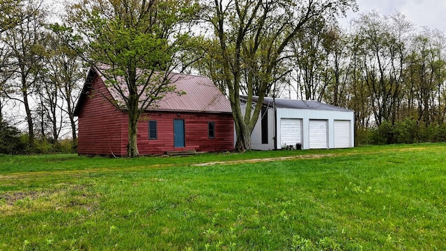 back of house with a garage, an outbuilding, and a yard