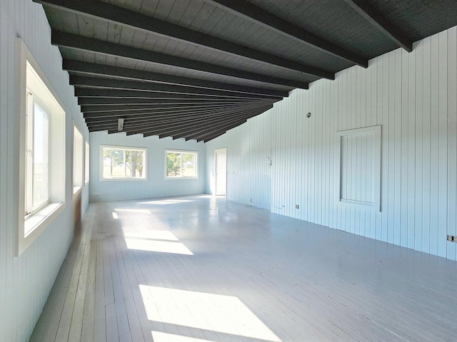 spare room featuring hardwood / wood-style flooring, vaulted ceiling with beams, and wooden walls